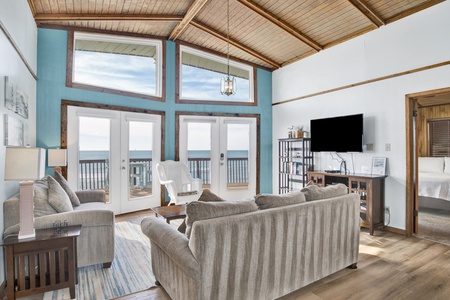 The living area has a large mounted TV and a shelf with books to enjoy