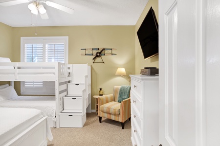 The second bedroom comes with a ceiling fan and a television