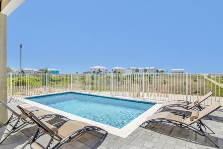 Private fenced beachside pool with lounge chairs