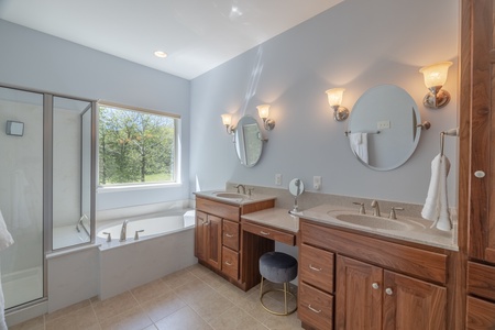 En Suite primary bathroom with double vanity sinks and a separate tub and standing shower