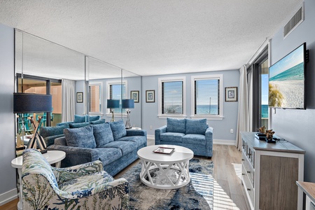 Sink into plush blue sofas and let the calming coastal palette surround you. Natural light pours through every window, inviting you to unwind in your bright, beautifully appointed living space.