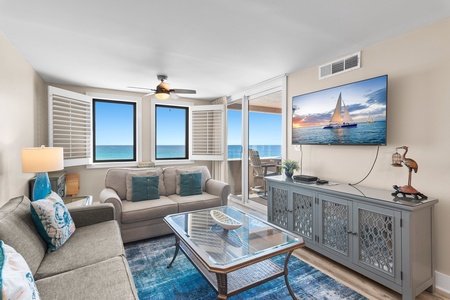 Relax in this bright oceanfront living space where coastal artwork and blue accents complement stunning sea views through your windows.