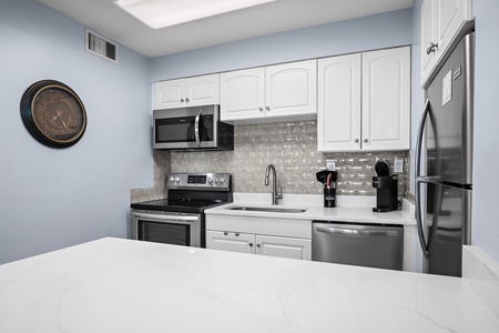 Your fully equipped kitchen features stainless appliances, white cabinetry, and gleaming countertops—perfect for preparing meals at home with plenty of space to spread out.