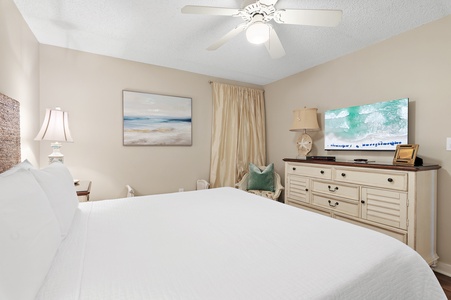 Sink into crisp linens in your peaceful bedroom, complete with coastal artwork, a ceiling fan for comfort, and a TV for unwinding after beach adventures.