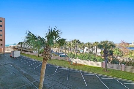 Beachfront property with convenient parking and palm-lined pathways leading to emerald waters and sandy shores.