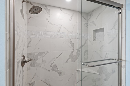 Step into your private shower oasis, where elegant marble-look tiles and modern fixtures create a spa-like retreat. The sleek glass door and polished details invite you to refresh and unwind.