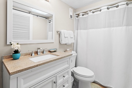 Freshen up in your clean, well-appointed bathroom with a soothing shower and plush towels waiting for you. Thoughtful touches like fresh flowers and a beige countertop create a calm, welcoming space.
