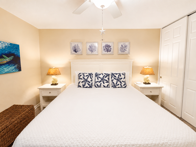 Sink into crisp linens and ocean-inspired comfort. Your coastal retreat awaits with a ceiling fan overhead and soft lighting to help you unwind.