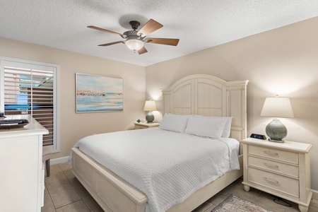 Drift into peaceful slumber in your serene bedroom featuring coastal artwork and gentle ceiling fan breezes.