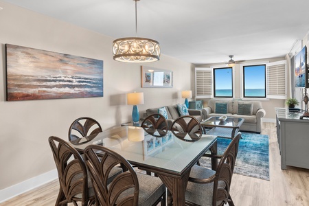 Relax in this bright oceanfront living space where coastal artwork and blue accents complement stunning sea views through your windows.