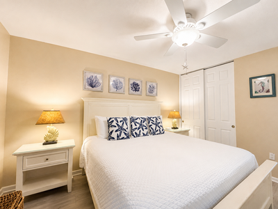 Sink into crisp white linens and coastal calm in your private bedroom retreat, where soft ceiling fan breezes and warm lamplight invite you to unwind completely.