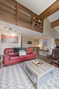 Relax in your bright living room with soaring ceilings, warm wood beams, and plush leather seating. A peaceful retreat with artwork and natural light for unwinding after mountain adventures.