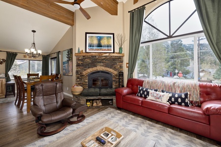Curl up in this inviting living room where rustic wood beams meet mountain views. Your cozy retreat features a stone fireplace, plush leather seating, and expansive windows framing nature outside.
