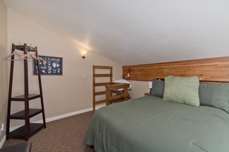 Your cozy loft retreat features a queen bed with sage linens, a charming bunk setup, and natural wood accents—perfect for families or groups seeking warmth and togetherness.
