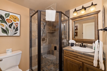 Refresh and recharge in your private bathroom featuring a spacious walk-in shower, warm wood vanity, and thoughtful touches like fluffy white towels waiting just for you.
