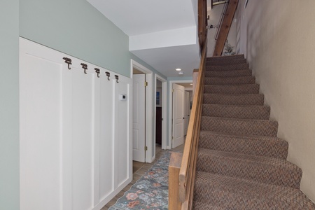 A welcoming entry with built-in hooks for your coats and bags, leading to carpeted stairs and connecting hallways—designed to keep your vacation stay organized and comfortable.