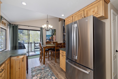 Your modern kitchen seamlessly flows into the dining area, where natural light pours through sliding glass doors to your private balcony. Warm wood floors and cabinetry create a welcoming mountain retreat atmosphere.