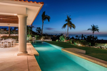 Right side view showing the patio, pool, and view of the ocean in the evening.