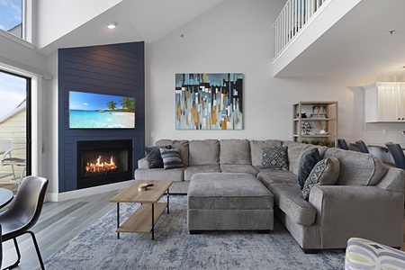 Sink into plush sectional seating while the fireplace crackles, creating your perfect gathering space beneath soaring ceilings.