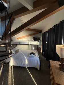 Unwind in your cozy sleeping quarters with modern furnishings and vaulted ceilings. Natural light filters through, creating a warm and restful ambiance for your stay.