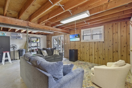Relax in your cozy basement retreat with plush seating, entertainment center, and rustic wood-beam charm perfect for unwinding.