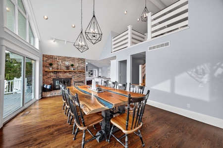 Gather around this stunning handcrafted dining table beneath soaring vaulted ceilings and geometric chandeliers. Natural light floods through the glass doors leading to your private deck, creating the perfect setting for memorable meals together.
