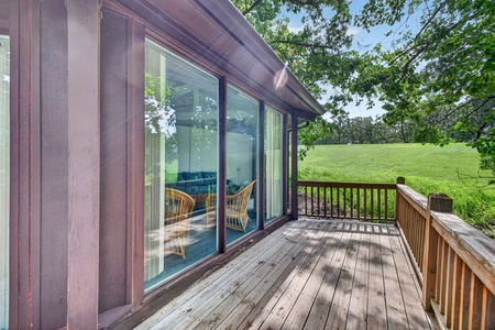 A private deck overlooking lush green fields and mature trees—your perfect spot to sip coffee or unwind with a book surrounded by nature's tranquility.