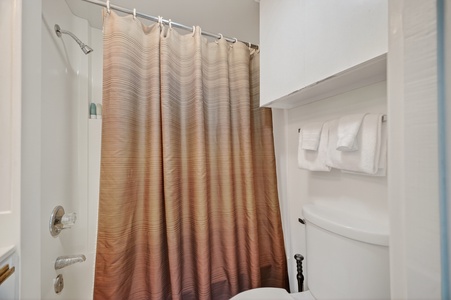 Step into your private bathroom where fresh towels await you. A soothing shower with warm, neutral tones invites you to unwind after a day of exploring.