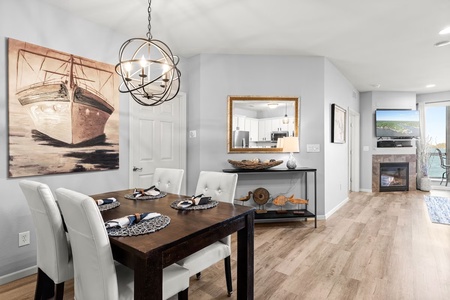 Gather around your elegant dining table beneath the stunning chandelier, where coastal charm meets modern comfort in your open-concept retreat.