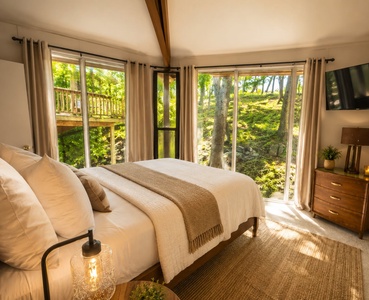 Wake up to soft sunlight filtering through towering trees and lush greenery right outside your window. This tranquil bedroom invites you to unwind in comfort, surrounded by nature's beauty and peaceful woodland charm.
