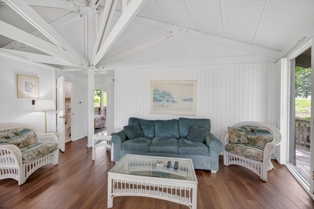 Relax in your airy coastal retreat with vaulted ceilings, warm wood floors, and charming wicker seating perfect for morning coffee or evening conversation as natural light pours in.
