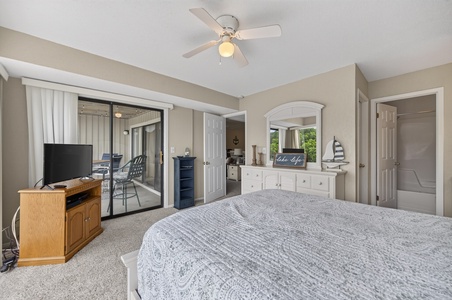 Your serene bedroom retreat features a plush bed, ceiling fan for comfort, TV for entertainment, and private balcony access—perfect for unwinding after a day of adventure.
