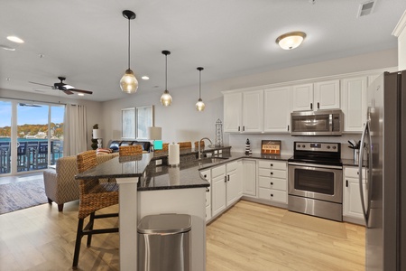 Cook and connect in this stunning open kitchen with modern appliances, granite counters, and waterfront views through expansive windows.