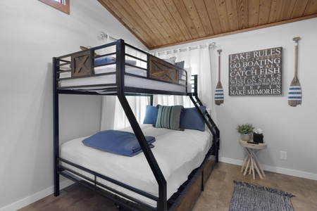 Your cozy lakeside bedroom features a spacious bunk bed with crisp linens, charming nautical decor, and a warm wood-paneled ceiling that invites restful nights after days on the water.