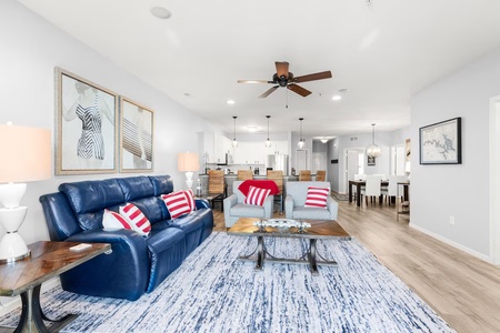 Relax in this beautifully appointed living space featuring a striking blue leather sofa, modern coastal decor, and an open-concept design that flows seamlessly into the kitchen.