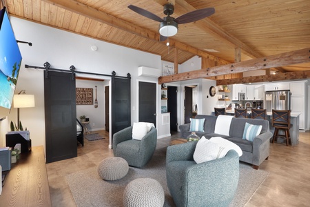 Unwind in your airy open-concept living space with vaulted wood ceilings, cozy seating, and modern farmhouse touches connecting you seamlessly to the full kitchen and dining area.
