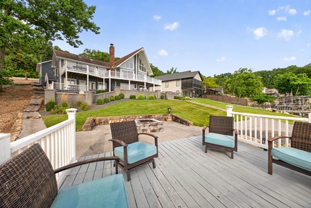 A spacious lakefront property featuring multiple levels of outdoor living spaces, including terraced lawns, a fire pit area, and expansive deck seating—perfect for gathering with friends and family while enjoying waterfront relaxation.