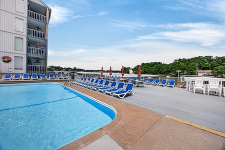 Waterfront property featuring an outdoor pool, sun loungers, and scenic views of the lake and surrounding greenery.