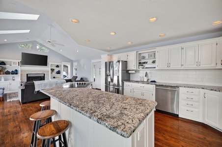 Your spacious open-concept living flows effortlessly from the granite-topped island to the cozy fireside seating area beneath soaring skylights and warm wood floors.