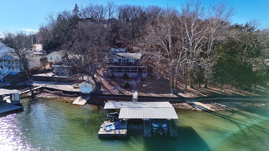 Lakefront property with private dock and boat slip, nestled among mature trees with clear water access.