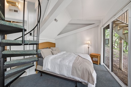 Your serene bedroom retreat features vaulted ceilings, crisp linens, and floor-to-ceiling windows that frame peaceful forest views, making every morning feel like a natural escape.