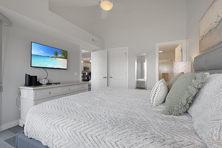 Sink into plush bedding while enjoying your favorite shows on the wall-mounted TV in this serene coastal-themed bedroom.