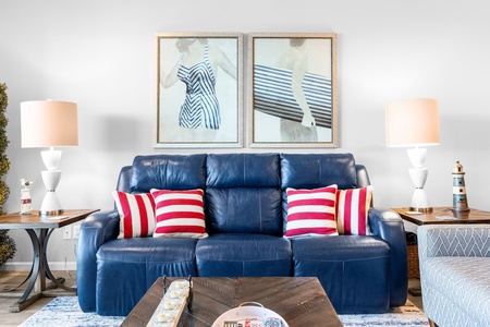 Sink into your cozy nautical retreat with a plush blue leather sofa adorned with cheerful red striped pillows.