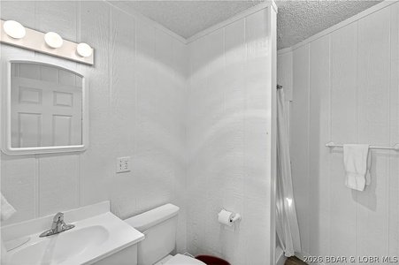 Bright white bathroom with tub-shower combo, vanity with mirror lighting, and fresh towels ready for your arrival.
