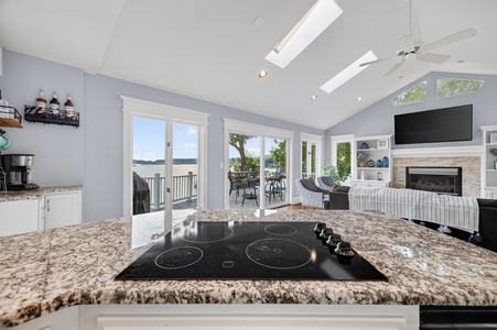 Your open-plan kitchen flows seamlessly into a bright living space where lake views greet you through floor-to-ceiling windows, and skylights bathe the room in natural warmth.