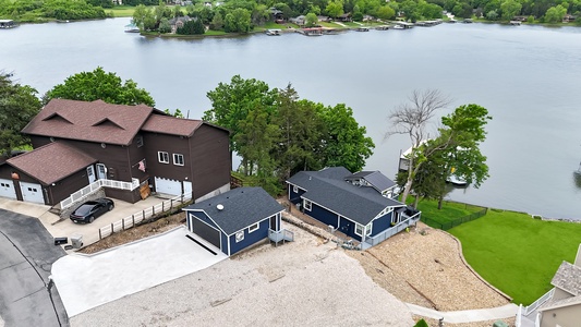 Aerial view captures waterfront vacation homes nestled along a serene lake, surrounded by lush trees and offering direct water access with private docks and boat slips.