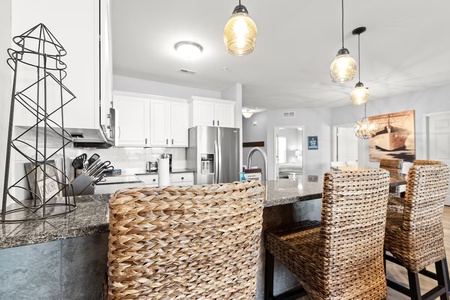 Your modern kitchen features granite countertops, stylish pendant lighting, and woven bar stools where you can enjoy meals together.