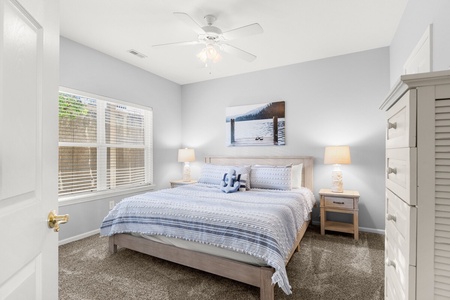 Sink into soft blue linens and drift off to peaceful sleep in this serene bedroom, where natural light and coastal artwork create your perfect retreat.