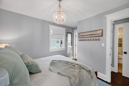 Unwind in your serene bedroom where soft gray walls and elegant chandelier lighting create a calming retreat perfect for restful nights.