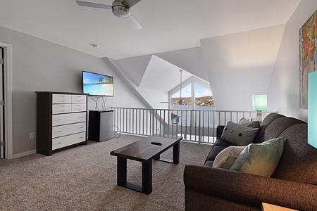 Relax in your cozy loft living space with comfortable seating, modern TV, and scenic windows overlooking the neighborhood below.